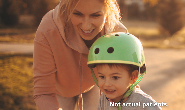 A lady helping her child ride a bike